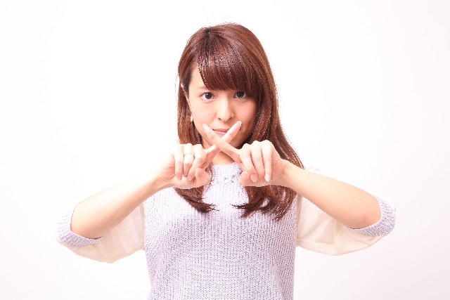 指でバツマークをする女性